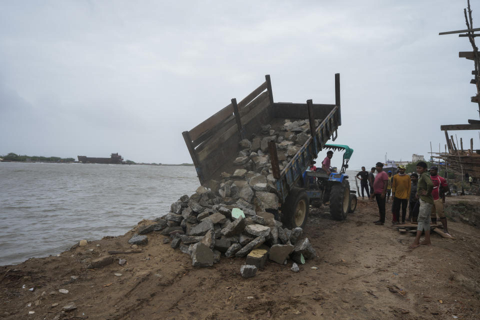 A tractor unloads stones to prevent sea water entering on the Arabia Sea coast at Mandvi in Kutch district of Gujarat state, India, Wednesday, June 14, 2023. With Cyclone Biparjoy expected to make landfall Thursday evening, coastal regions of India and Pakistan are on high alert. (AP Photo/Ajit Solanki)