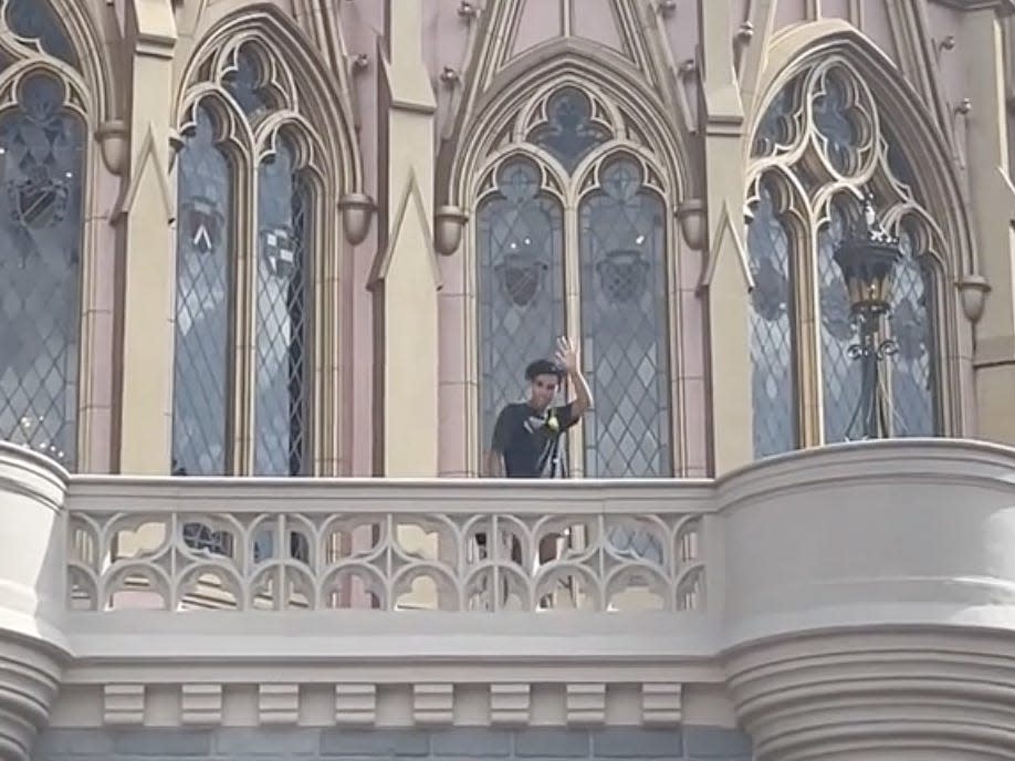 A Disney Parkgoer stands atop Cinderella Castle.