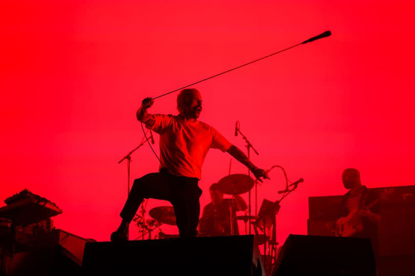 Silhouette of Joe Talbot of Idles performing on a red background