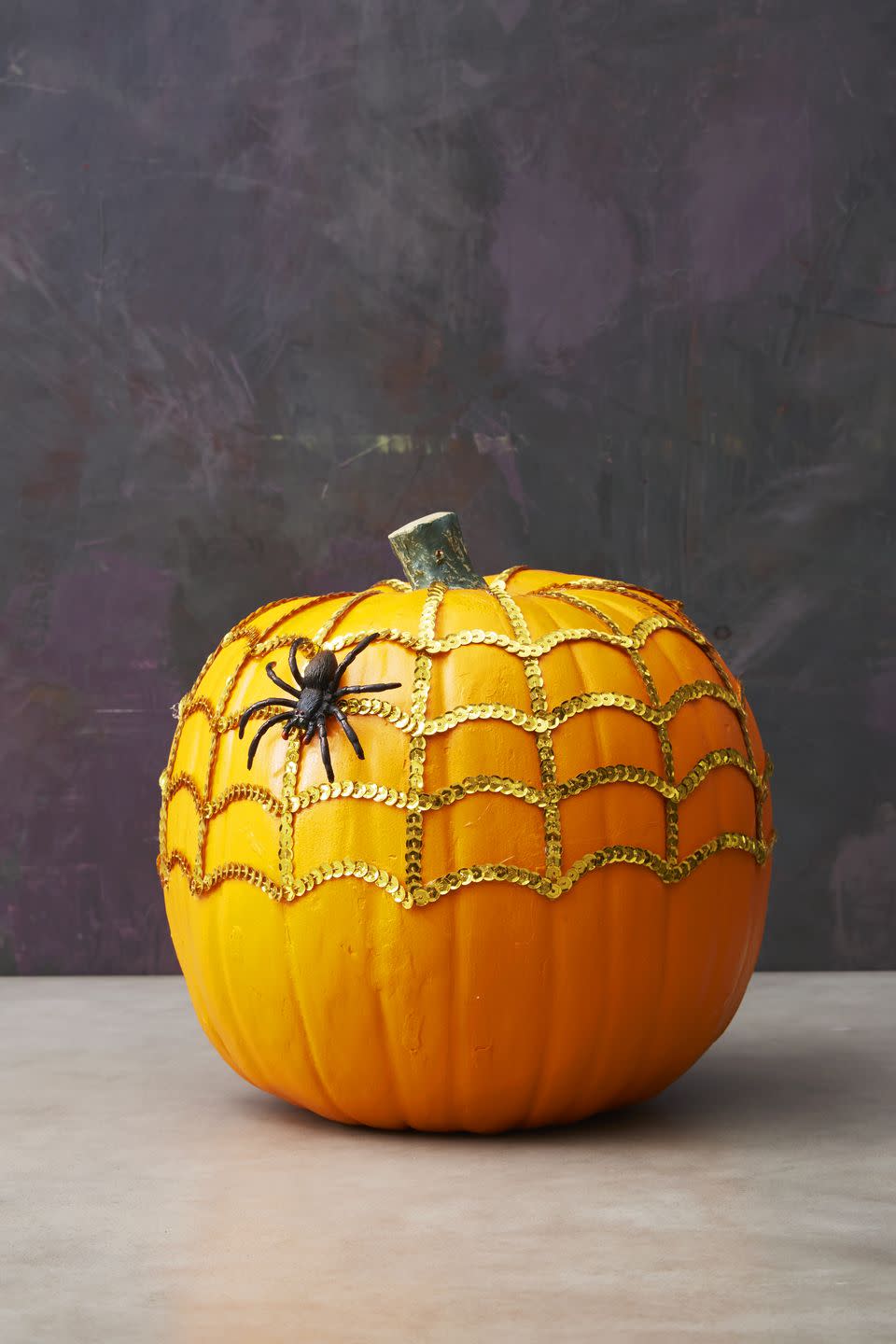 <p>Using hot glue, place strings of sequins going about halfway down the pumpkin. Next, go horizontal with curved lines to complete the cobweb. A spider is optional but encouraged!</p><p><a class="link " href="https://www.amazon.com/Expo-International-20-Yard-Starlight-Hologram/dp/B00G02ZTA8/?tag=syn-yahoo-20&ascsubtag=%5Bartid%7C10055.g.1714%5Bsrc%7Cyahoo-us" rel="nofollow noopener" target="_blank" data-ylk="slk:SHOP SEQUINS;elm:context_link;itc:0;sec:content-canvas">SHOP SEQUINS</a><br></p>