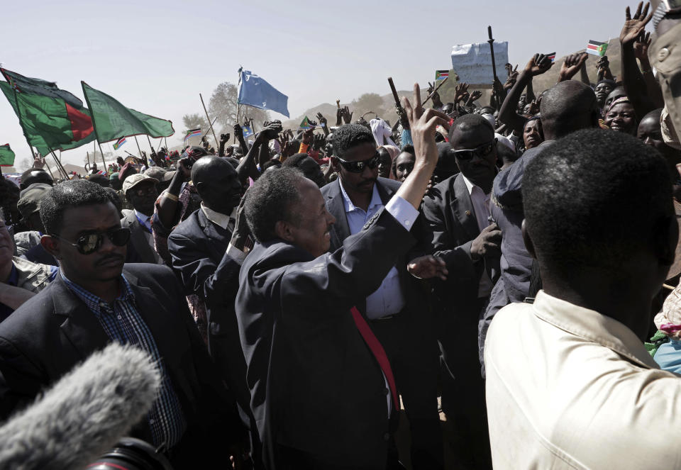 Sudanese Prime Minister Abdalla Hamdok, center, waves to people in the conflict-affected remote town of Kauda, Nuba Mountains, Sudan, Jan. 9, 2020. Hamdok, accompanied by United Nations officials, embarked on a peace mission Thursday to Kauda, a rebel stronghold, in a major step toward government efforts to end the country’s long-running civil conflicts. (AP Photo/Nariman El-Mofty)