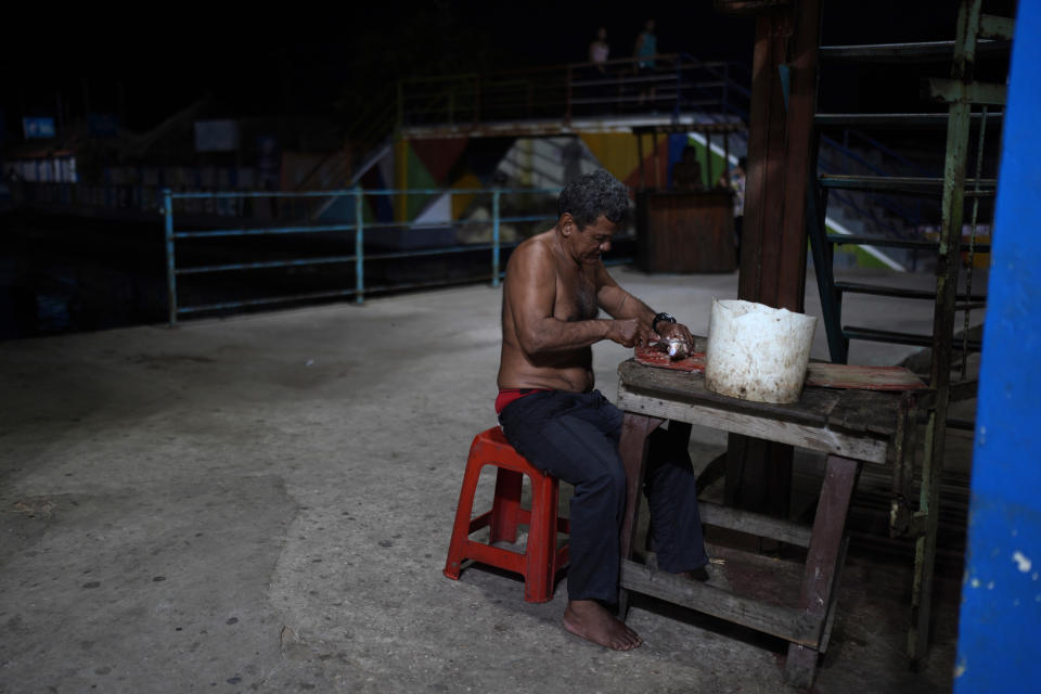 Ignacio limpia un pescado que obtuvo del Lago de Maracaibo, en el barrio de Santa Rosa de Agua de Maracaibo, Venezuela, el miércoles 9 de agosto de 2023. (AP Foto/Ariana Cubillos)