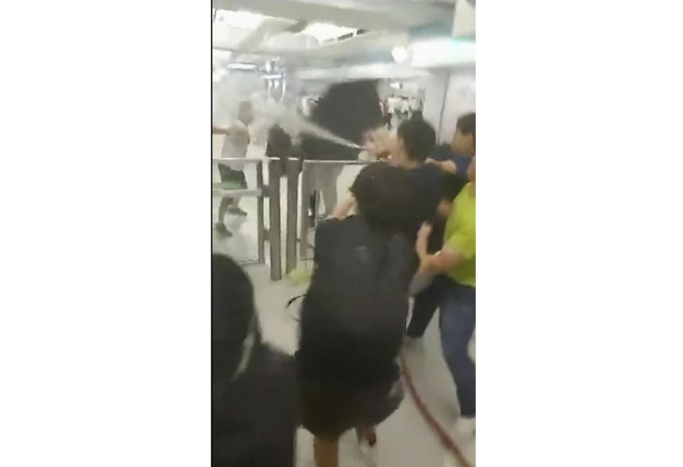 This Sunday, July 21, 2019, image made off from a video, shows protesters using water hose on assailants at Yuen Long MTR train station in Hong Kong. Protesters trying to return home were attacked inside a train station by assailants who appeared to target the pro-democracy demonstrators. (Lam Cheuk-ting via AP)