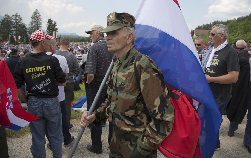 FILE - In this Saturday, May 12, 2018 file photo, a uniformed man carries a Croatian flag during a commemoration ceremony in Bleiburg, Austria. Thousands will gather in a field in southern Austria on Saturday, May 18, 2018, for an annual event to commemorate the massacre of tens of thousands mostly pro-Nazi soldiers known as Ustashas who fled to the village of Bleiburg in May 1945 amid a Yugoslav army offensive, only to be turned back by the British military and into the hands of revengeful antifascists. (AP Photo/Darko Bandic, File)