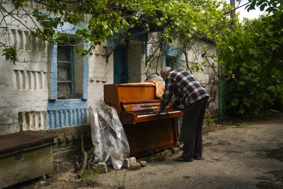 Anatolii Virko toca un piano fuera de una casa que probablemente resultó dañada por un ataque ruso, el 19 de mayo de 2022, en el poblado de Velyka Kostromka, Ucrania. (AP Foto/Francisco Seco)