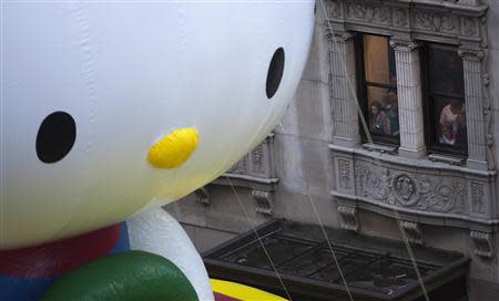 People look on as the Hello Kitty balloon float makes its way down 6th Avenue during the 87th Macy's Thanksgiving day parade in New York November 28, 2013. REUTERS/Carlo Allegri