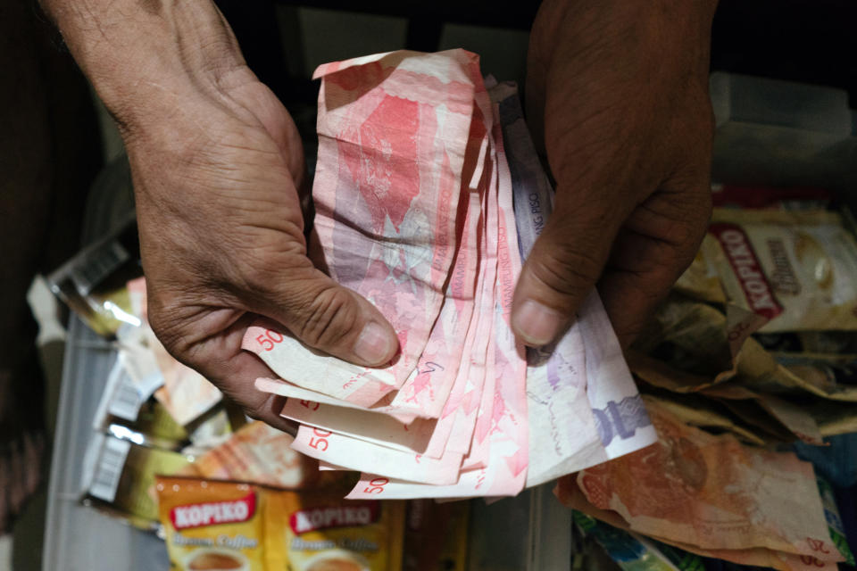 A man counts Philippine Peso bills inside a store in Manila, Philippines. (Photo: Getty Images)