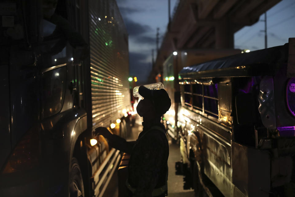 A police officer inspects a truck driver at a checkpoint during a stricter community quarantine as a precaution against the spread of the new coronavirus disease at the outskirts of Marikina City, Philippines on Friday, August 6, 2021. Thousands of people jammed coronavirus vaccination centers in the Philippine capital, defying social distancing restrictions, after false news spread that unvaccinated residents would be deprived of cash aid or barred from leaving home during a two-week lockdown that started Friday. (AP Photo/Basilio Sepe)