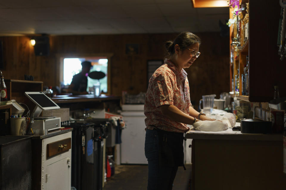 Yokie Johnson prepares a takeout order at the restaurant she owns with her husband in Fishtail, Mont., Friday, June 17, 2022. The main road into Fishtail was washed away by the recent floodwaters and Johnson worries the lack of traffic will hurt their business. For Johnson, the business was a dream come true. She had beat cancer a few years ago, but it returned late last year in a more aggressive form and has spread across her body. "I'm not sure how much time I have left, so the time I have left I want to be with my family, work with them every day, see them every day," she said. (AP Photo/David Goldman)