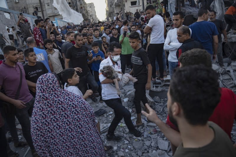 <cite>2023年10月21日，加薩走廊汗尤尼斯遭受以色列空襲後，一名兒童從廢墟中被抱出。（美聯社）</cite>