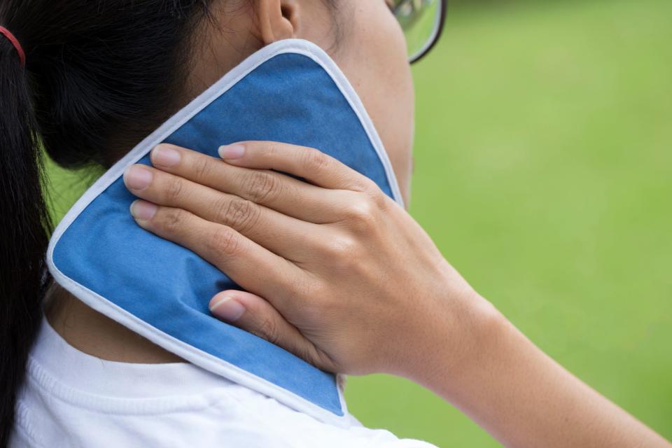 Woman putting an ice pack on her neck pain.