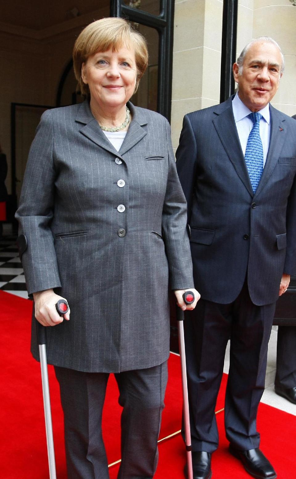 Head of the Organization for Economic Co-operation and Development (OECD) Angel Gurria, right, poses for photographers with Germany's Chancellor Angela Merkel prior to their meeting at the OECD headquarters in Paris, Wednesday, Feb. 19, 2014. Merkel uses crutches after a skiing accident. (AP Photo/Michel Spingler)