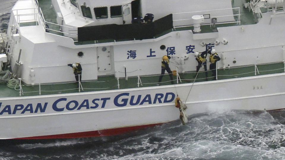 Japanese coast guard members pick up a floating object as they conduct search and rescue operation in the waters off Yakushima Island, Kagoshima prefecture, southern Japan, Nov. 30. (Kyodo News via AP)