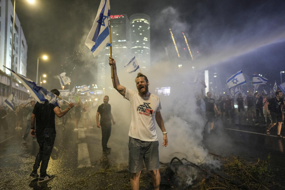 Israeli police use a water cannon to disperse demonstrators blocking the freeway during a protest against plans by Prime Minister Benjamin Netanyahu's government to overhaul the judicial system in Tel Aviv, Israel, Wednesday, July 5, 2023. (AP Photo/Oded Balilty)