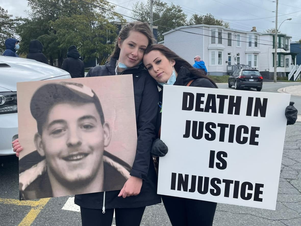 Samantha (left) and Courtney Pike stand outside the of the HMP to protest lack of addiction help after their brother died by suicide.  (Meg Roberts/CBC - image credit)