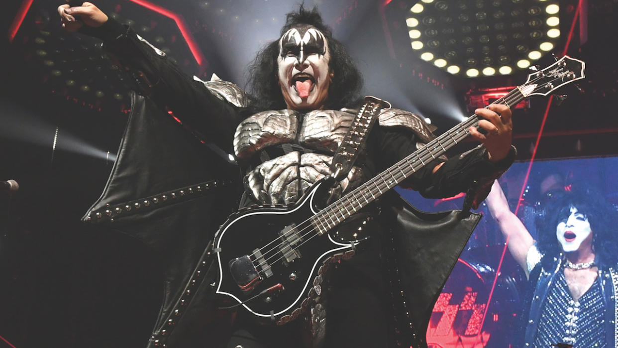  Gene Simmons on stage with Kiss in makeup with his tongue sticking out. 