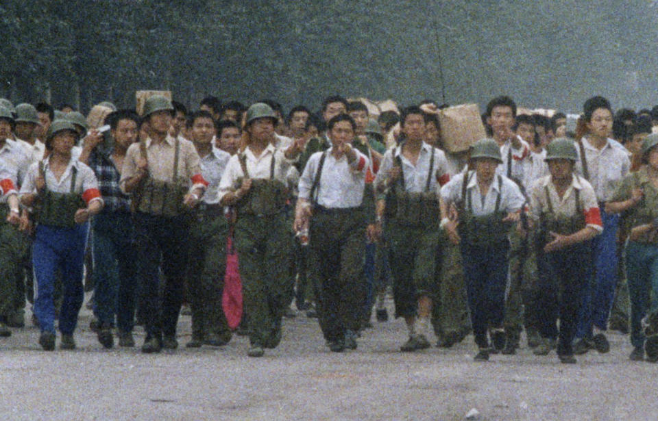 In this June 6, 1989, photo, Chinese soldiers marching away from Tiananmen point out an an Associated Press reporter taking photos, which was against the regulations of martial law that had been declared May 20 and later gave chase, firing twice before the reporter escaped near the International Hotel in Beijing. The Chinese army had fought its way into Tiananmen Square the night of June 3-4 to reclaim the square from student-led demonstrators who had been protesting for democratic reforms for three weeks. (AP Photo/Terril Jones)