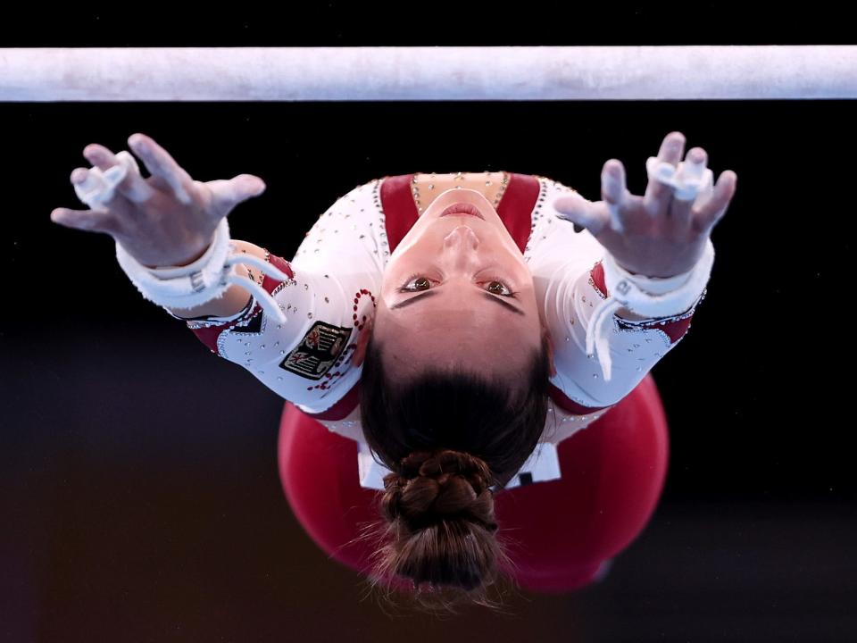 Pauline Schaefer-Betz of Team Germany reaches for the uneven bars, upside down.