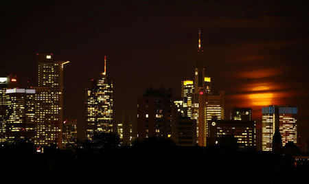 FILE PHOTO - The moon is partly covered by clouds as it rises above the skyline of Frankfurt, Germany, early evening November 14, 2016. REUTERS/Kai Pfaffenbach/File Photo