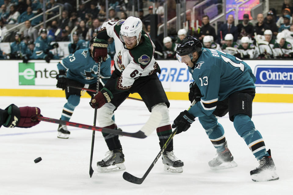 Arizona Coyotes left wing Lawson Crouse (67) gets possession from San Jose Sharks center Nick Bonino (13) during the second period of an NHL hockey game Sunday, March 20, 2022, in San Jose, Calif. (AP Photo/John Hefti)