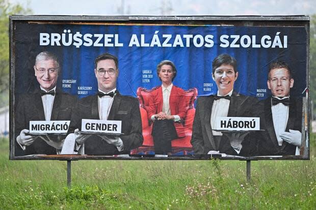 An election billboard in Budapest depicts Hungarian politicians dressed as waiters surrounding Ursula von der Leyen, the European Commission president. The text on the top reads ‘Brussels' humble servants' with the letters replaced with a dollar sign. The billboard was paid for by the governing right-wing Fidesz party, which claims that opposition parties serve foreign interests and undermine Hungarian sovereignty.