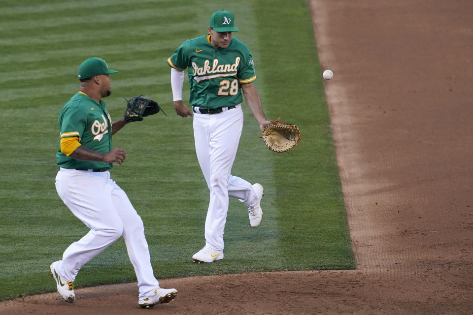 Oakland Athletics first baseman Matt Olson (28) flips the ball to pitcher Frankie Montas on a ground out hit into by Kansas City Royals' Nicky Lopez during the third inning of a baseball game in Oakland, Calif., Thursday, June 10, 2021. (AP Photo/Jeff Chiu)