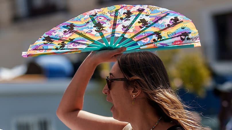 Μια γυναίκα προστατεύει τον εαυτό της από τον ήλιο με έναν ανεμιστήρα στη Μαδρίτη, Ισπανία, 10 Ιουλίου 2023.