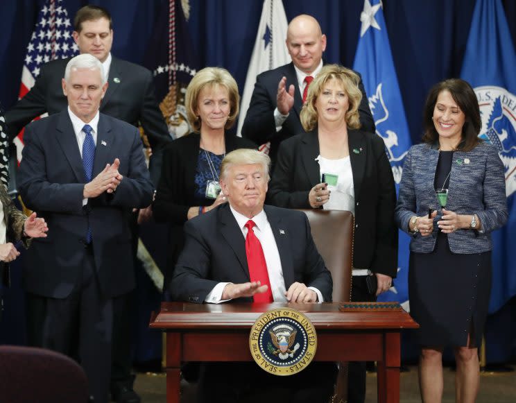 President Trump, accompanied by Vice President Mike Pence and others, taps on the table after signing an executive order for immigration actions to build border wall, Jan. 25, 2017, at the Homeland Security Department in Washington. (AP Photo/Pablo Martinez Monsivais)