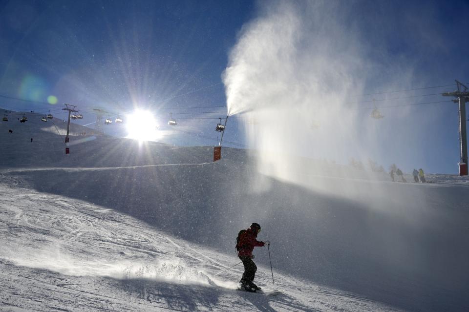 A skier descends a slope in front of a snow cannon, in Val d'Isere, French Alps, in 2012. Snowmaking can help ski areas ease the threat of climate change, but only up to a point, experts say. "It is not a climate solution," the ski industry says.