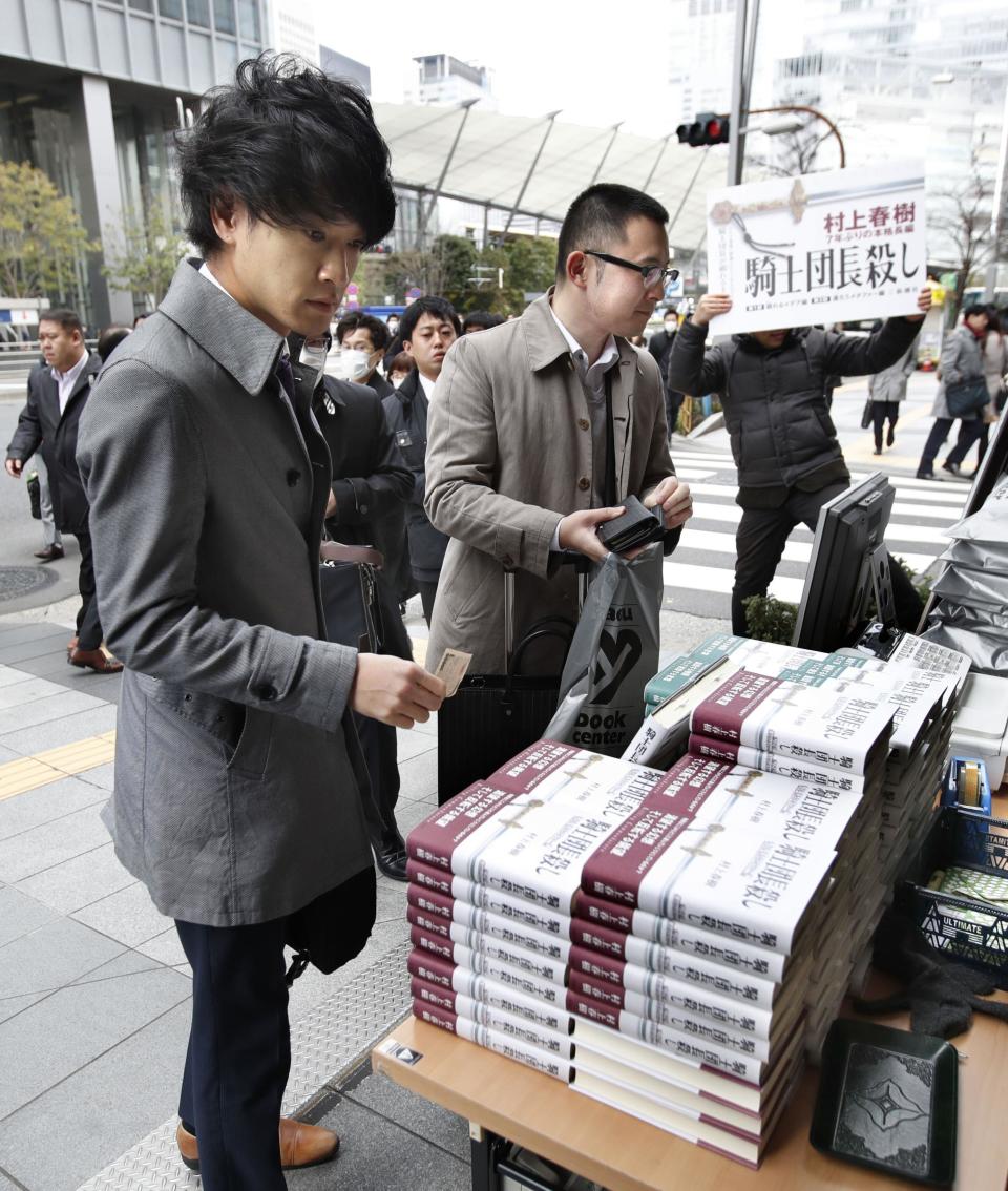 People buy copies of the new book written by Haruki Murakami at a make shift corner outside a book store in Tokyo Friday, Feb. 24, 2017. Murakami's new book "Kishidancho Goroshi," or "Killing Commendatore," is a two-part story about a 36-year-old portrait painter and the mysterious incidents that happen after his wife divorces him and he moves into an old house on a mountainside west of Tokyo. (Fumine Tsutabayashi/Kyodo News via AP)