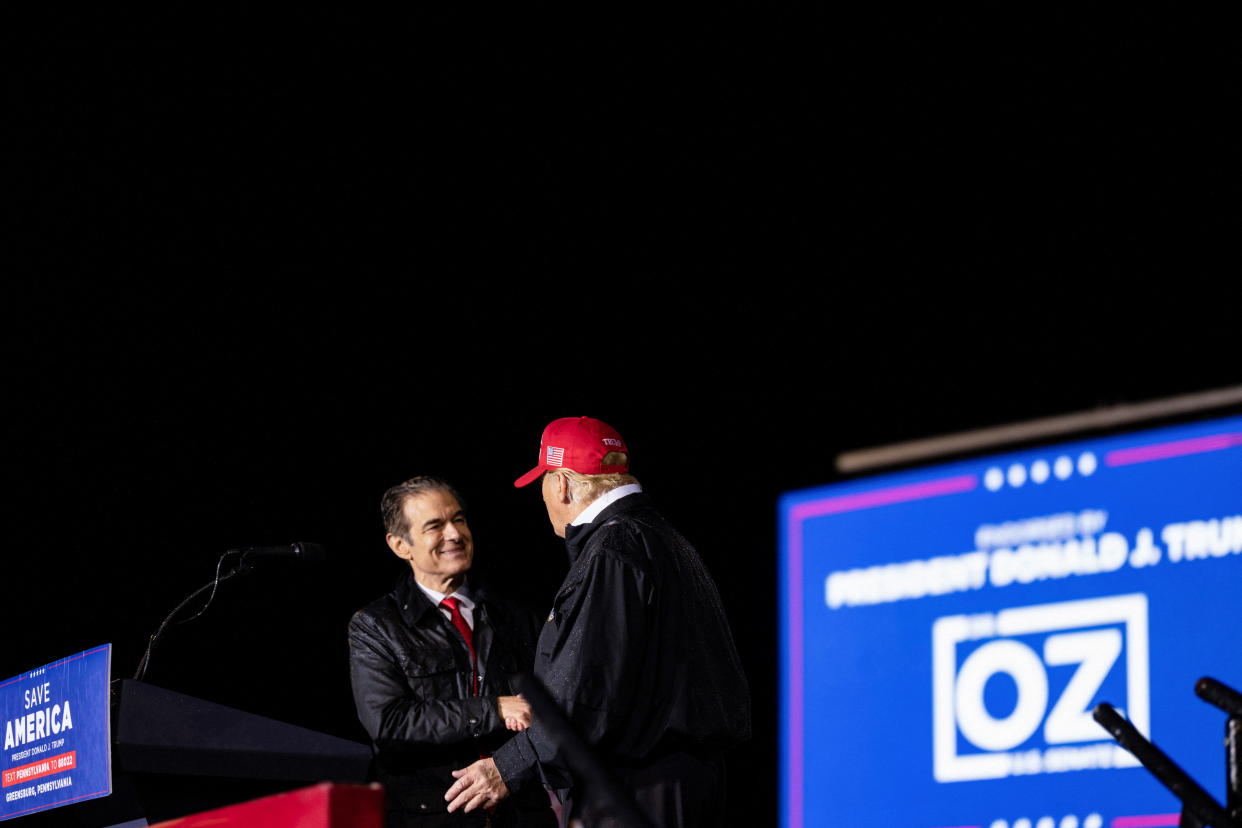 A beaming Oz shakes hands with his patron, Trump.