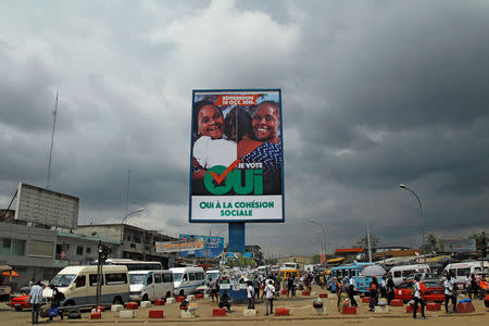 People walk past a campaign billboard of Ivory Coast's ruling party ahead of the referendum for a new constitution, in Abidjan, Ivory Coast October 27, 2016. REUTERS/Luc Gnago