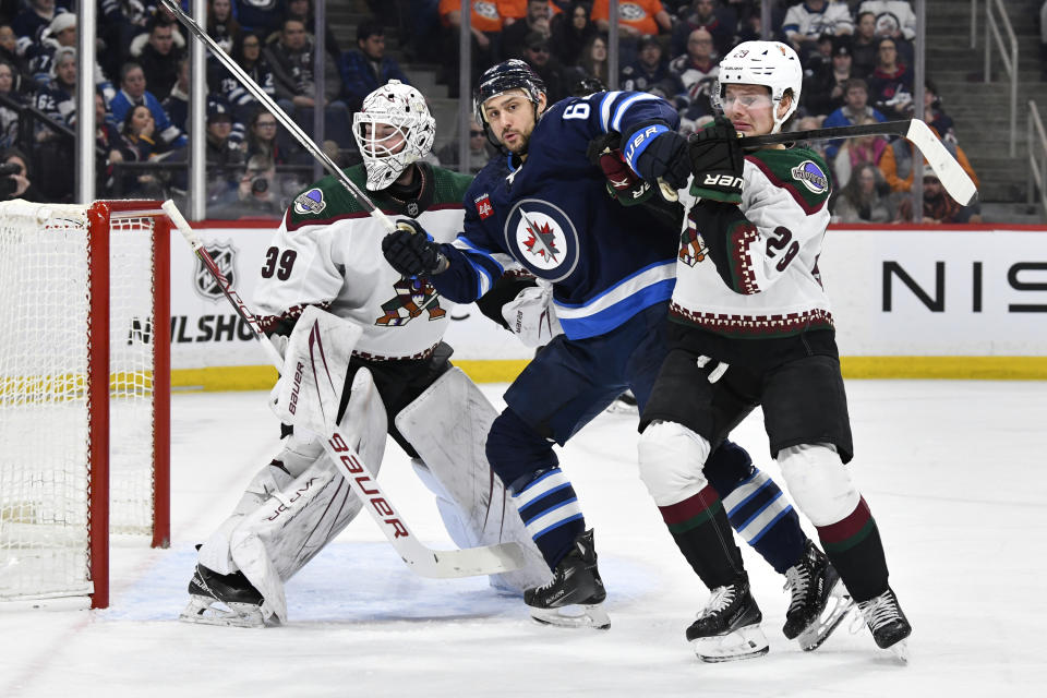 Arizona Coyotes' Barrett Hayton (29) defends against Winnipeg Jets' Nino Niederreiter (62) in front of his goaltender Connor Ingram (39) during the second period of an NHL hockey game in Winnipeg, Manitoba on Sunday, Feb. 25, 2024. (Fred Greenslade/The Canadian Press via AP)