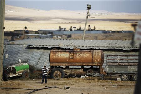 A boy stands in front of a shed in the Bedouin village of Bir Mshash in Israel's southern Negev December 10, 2013. REUTERS/Amir Cohen