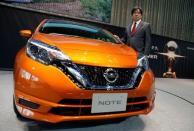 Nissan Executive Vice President Hideyuki Sakamoto poses with the hybrid version of Nissan Note, which uses the carmaker's e-Power system, in the showroom at the carmaker's headquarters in Yokohama, Japan, January 13, 2017. Picture taken January 13, 2017. REUTERS/Toru Hanai