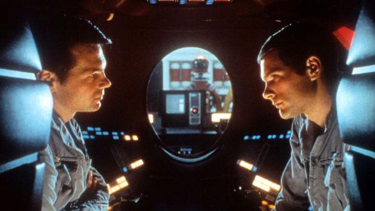 Los astronautas Poole y Bowman dentro de una cápsula con la lente roja de HAL en el fondo