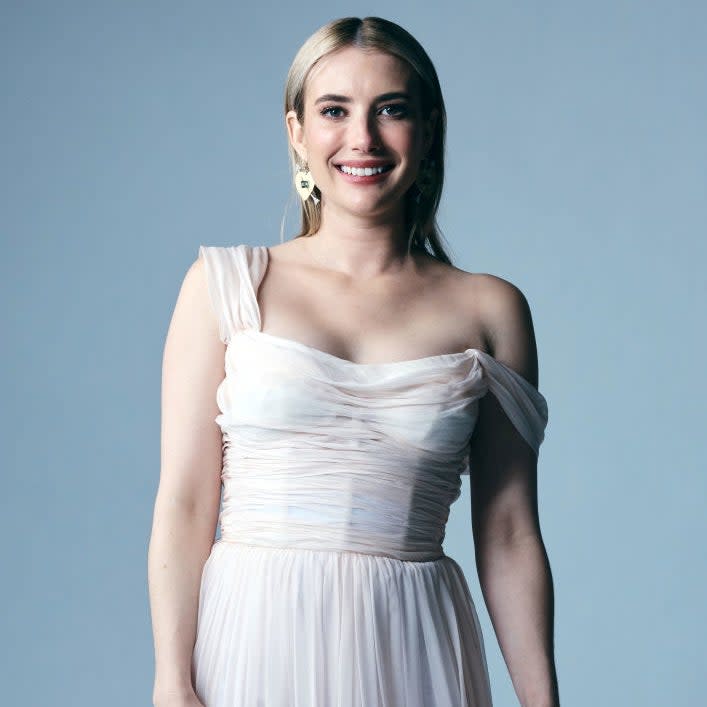 Emma in a one-shoulder, pleated gown smiling at the camera