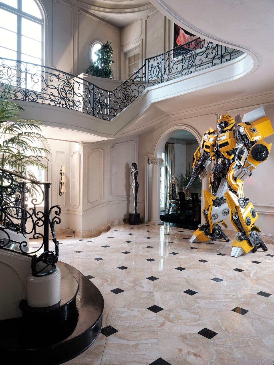 The marble entrance with frame moldings and a filigreed staircase railing came with the French Chateau–style mansion in Buckhead, Atlanta. “The only thing I added was my Bumblebee!” says the owner, actor Tyrese Gibson, who purchased the Transformer sculptures for what will eventually be Voltron Studios Hollywood, a full-service film studio he is building in Atlanta. “The kids and the adults love Bumblebee and Optimus Prime. They are such random things to see, and they are like 16 feet tall.”
