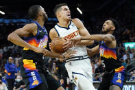 Denver Nuggets forward Michael Porter Jr., center, is pressured by Phoenix Suns guard Cameron Payne (15) and Phoenix Suns forward Mikal Bridges during the first half of an NBA basketball game, Wednesday, Oct. 20, 2021, in Phoenix. (AP Photo/Matt York)