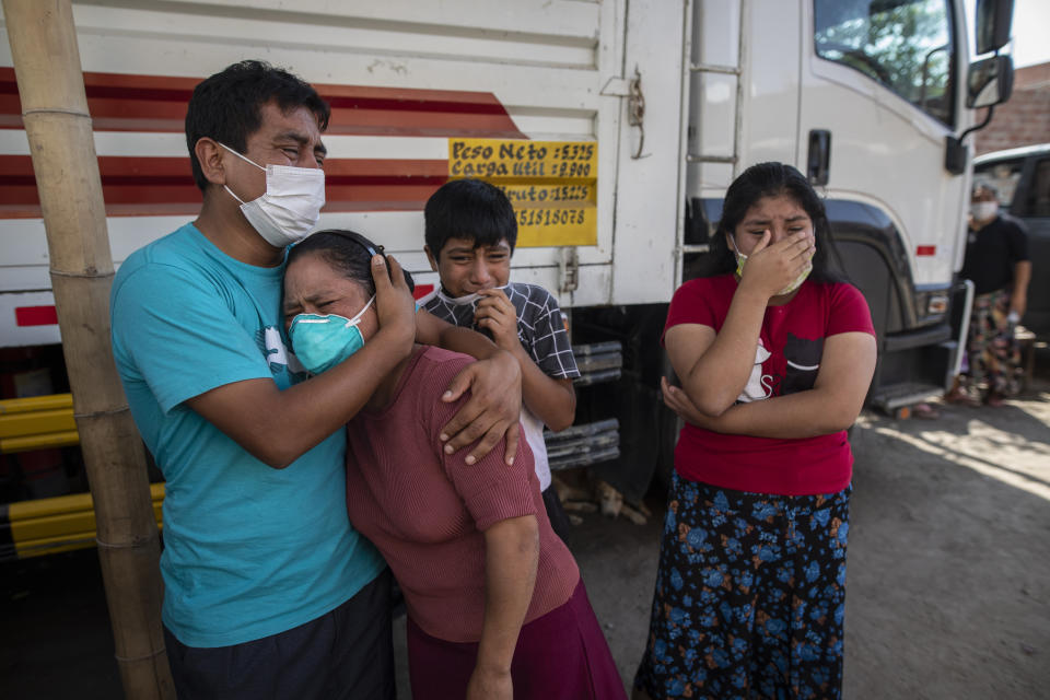 Family members grieve as they watch Piedrangel funeral home workers remove the body of a relative suspected of dying from the new coronavirus, in Lima, Peru, Monday, May 11, 2020. Despite strict measures to control the virus, this South American nation of 32 million has become one of the countries worst hit by the disease. (AP Photo/Rodrigo Abd)