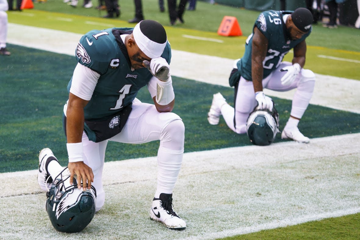 Philadelphia Eagles quarterbacks Jalen Hurts (1) kneels with running back Miles Sanders (26) during the NFL football game against the Jacksonville Jaguars, Sunday, Oct. 2, 2022, in Philadelphia. Public display of faith is nothing new in football or sports.(AP Photo/Chris Szagola, File)