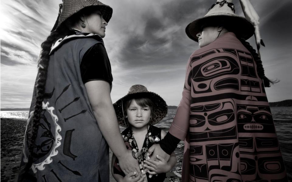 Tulalip tribe members Darkfeather, Bibiana, and Eckos Ancheta pose for a portrait.