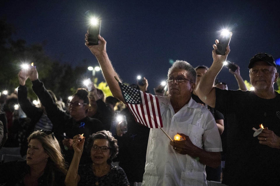 Miguel Ruiz, center, and his wife, Sara, seated, attend a vigil in Palmdale, Calif., for Los Angeles County Sheriff's Deputy Ryan Clinkunbroomer at the Palmdale Sheriff's Station, Sunday, Sept. 17, 2023, after the training officer was shot and killed in his patrol car at an intersection a day earlier. The Ruiz's son is a deputy at the Palmdale station. (Sarah Reingewirtz/The Orange County Register via AP)