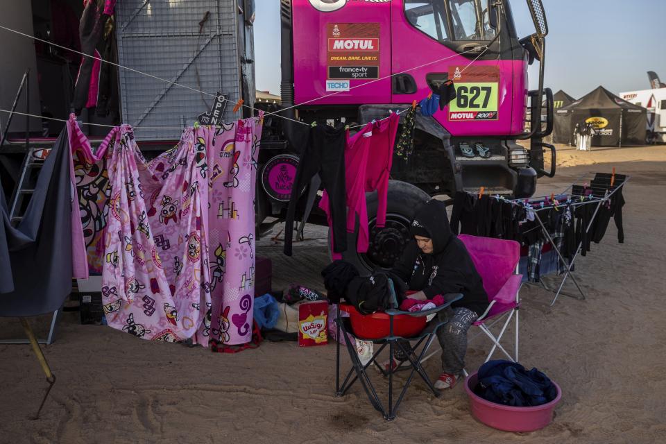 In this Monday, Jan. 13, 2020 photo, a team member of driver Camelia Liparoti, of Italy, and co-driver Annett Fischer, of Germany, does the laundry after stage eight of the Dakar Rally in Wadi Al Dawasir, Saudi Arabia. Formerly known as the Paris-Dakar Rally, the race was created by Thierry Sabine after he got lost in the Libyan desert in 1977. Until 2008, the rallies raced across Africa, but threats in Mauritania led organizers to cancel that year's event and move it to South America. It has now shifted to Saudi Arabia. The race started on Jan. 5 with 560 drivers and co-drivers, some on motorbikes, others in cars or in trucks. Only 41 are taking part in the Original category. (AP Photo/Bernat Armangue)