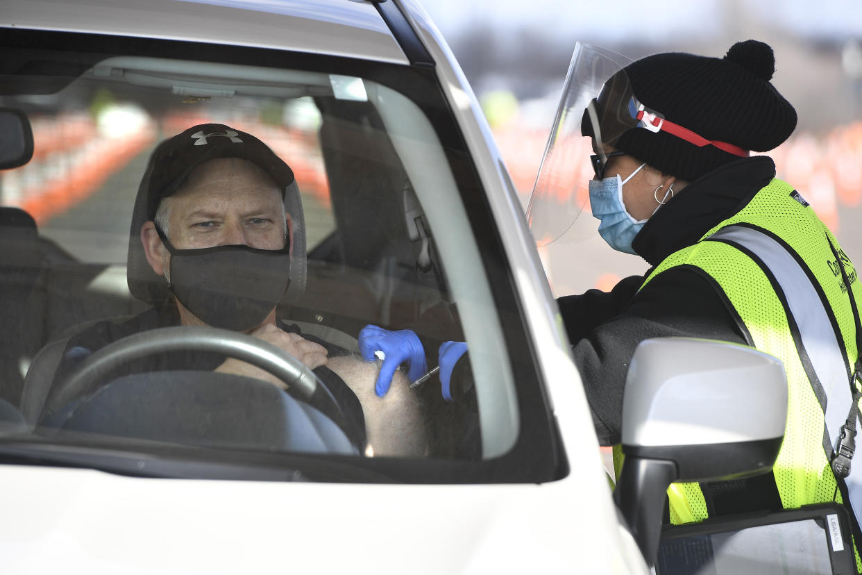 Educator John Cormier of Norwich, Conn., receives a shot from LPN Lizmary Reyes, right, on opening day of the Connecticut's largest COVID-19 Vaccination Drive-Through Clinic Monday, Jan. 18, 2021, in East Hartford, Conn. The former Pratt & Whitney Runway has been converted into a ten-lane, drive-through COVID-19 Mass Vaccination Clinic, with the Pfizer-BioNTech vaccine being administered by Community Health Center, Inc. (CHC). Vaccinations are by appointment only to eligible individuals in Phase 1a and 1b through Connecticut's 211 system or the CDC's Vaccine Administration Management System. (AP Photo/Jessica Hill)