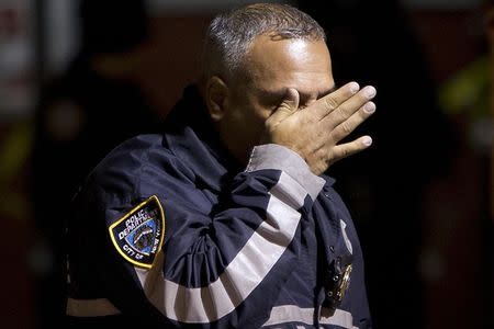 A police officer wipes tears away from his face as he walks away from the scene of a shooting where two New York Police officers were shot dead in the Brooklyn borough of New York, December 20, 2014. REUTERS/Carlo Allegri