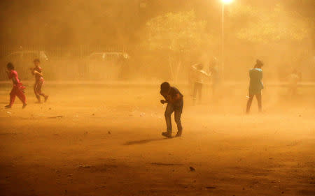 Children cover themselves during a dust storm in New Delhi, India May 13, 2018. REUTERS/Adnan Abidi