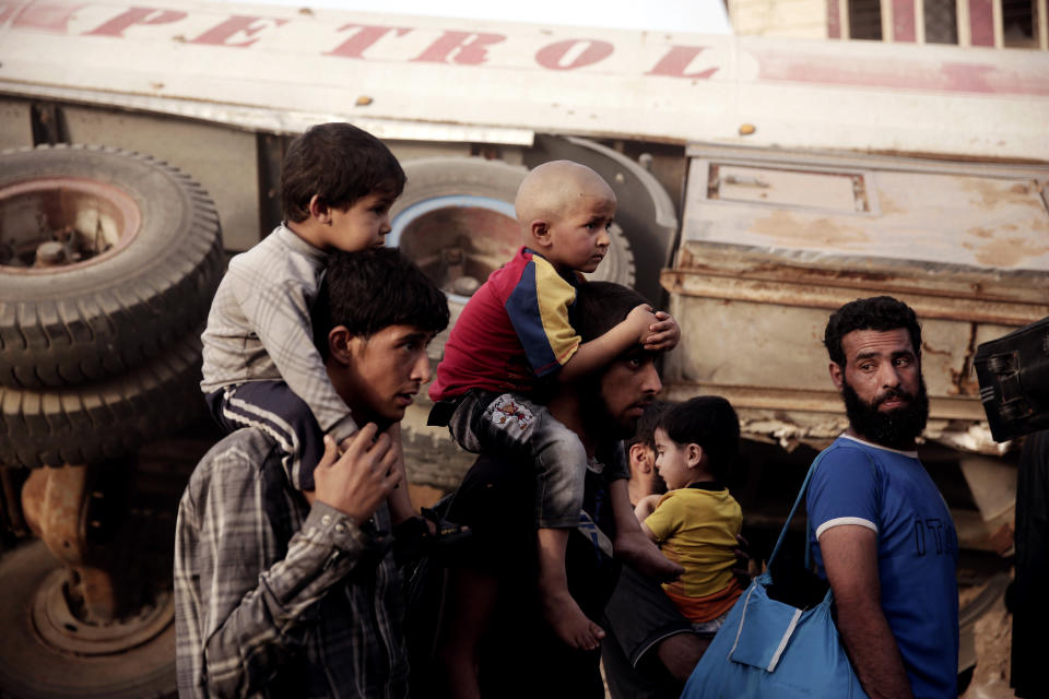 FILE - In this May 10, 2017, file photo, men and children flee heavy fighting between Islamic State militants and Iraqi special forces in Mosul, Iraq. An international charity said Tuesday, April 30, 2019, that an estimated 45,000 children in Iraq who were born under the rule of the Islamic State group are being excluded from society because the government denies them documentation and ID papers. (AP Photo/Maya Alleruzzo, File)