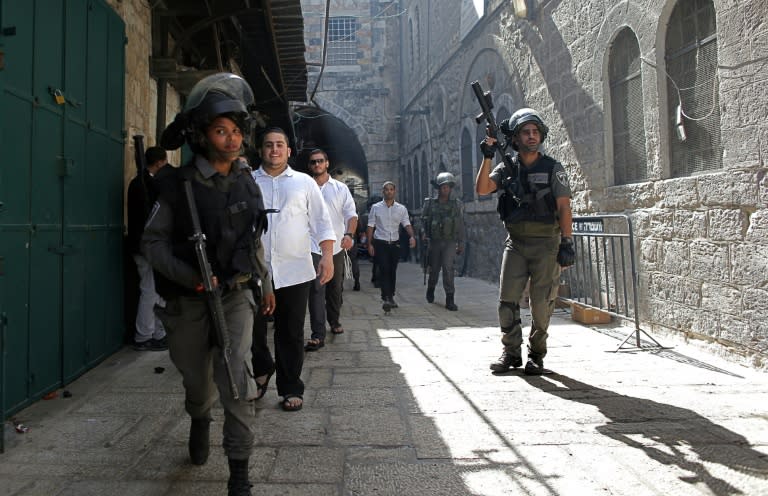 Israeli security forces escort Jewish worshipers coming from the Western Wall, Judaism's holiest site, as they cross al-Wad street in the Muslim quarter of Jerusalem's Old City, on September 15, 2015