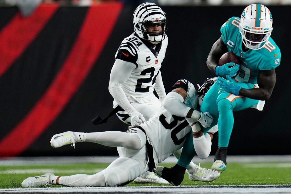 Dolphins receiver Tyreek Hill tries to extend the play after a reception against the Bengals last Thursday with safety Jessie Bates III hanging on.